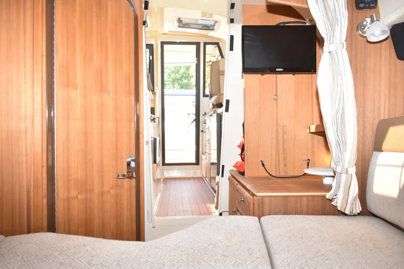 Slide: The Image of 2024 Ranger Tugs R-27 interior with wood finish, TV, and cozy seating area. - 45