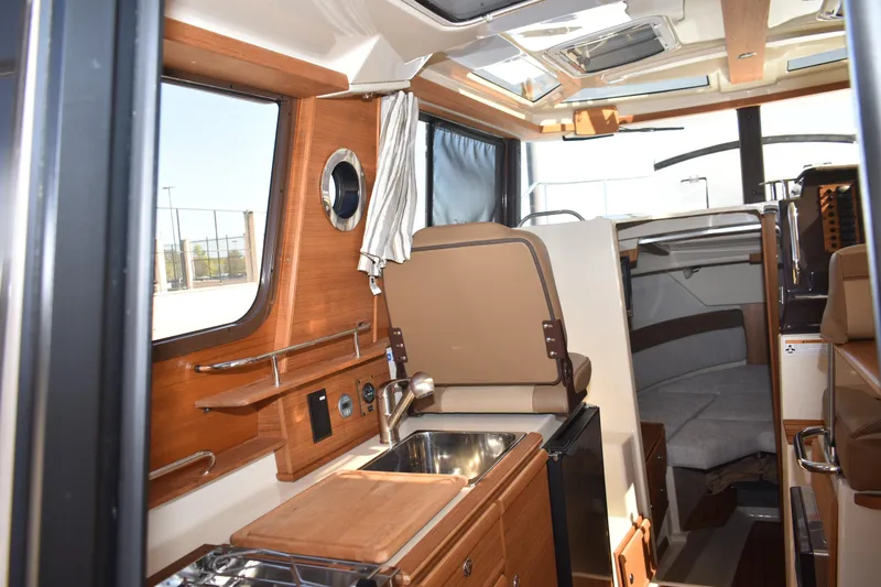 Slide: The Image of 2024 Ranger Tugs R-27 interior with modern kitchen and cozy seating area. - 49