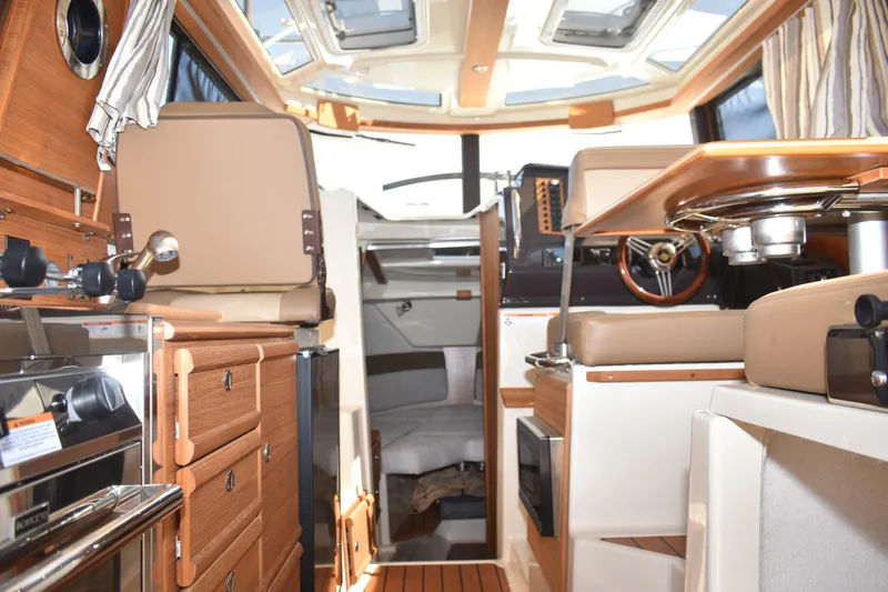 Slide: The Image of Interior of 2024 Ranger Tugs R-27 boat, featuring wood cabinetry and modern seating. - 51