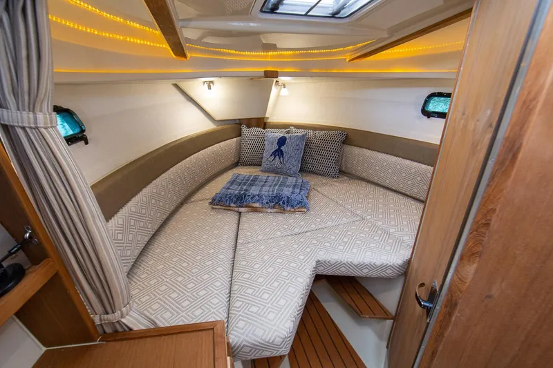 Slide: The Image of Manufacturer Provided Image: 2024 Ranger Tugs R-27 cabin interior with cozy bed and ambient lighting. - 58