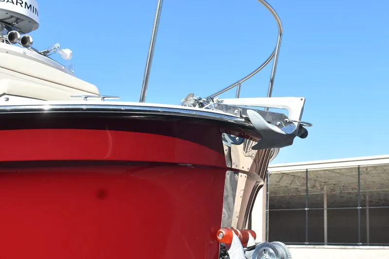 Slide: The Image of 2024 Ranger Tugs R-27 boat with red hull and anchor, under clear blue sky. - 7