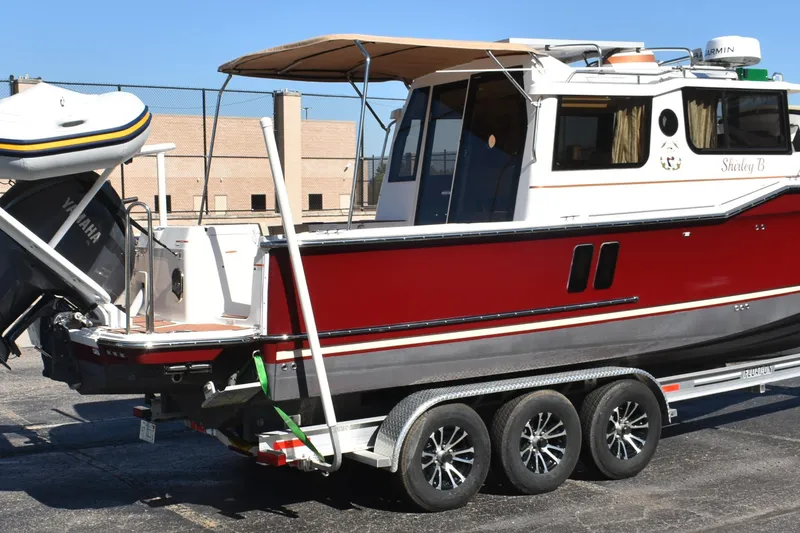 Slide: The Image of 2024 Ranger Tugs R-27 boat on trailer, red and white exterior, Yamaha engine. - 9