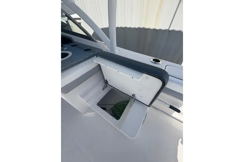 Slide: The Image of 2021 Robalo R317 Dual Console boat storage compartment with open lid and visible contents. - 10
