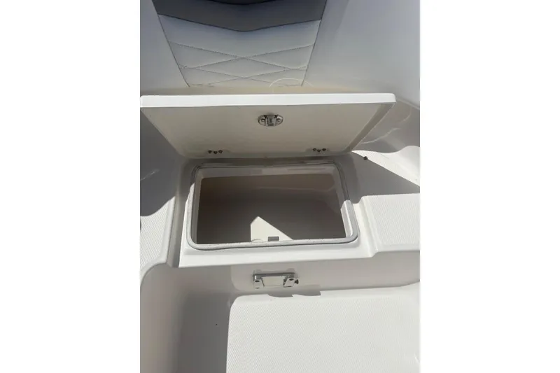 Slide: The Image of 2021 Robalo R317 Dual Console storage compartment, open lid, white interior. - 18