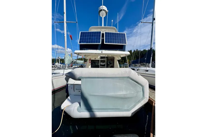 Slide: The Image of 1998 Bayliner 3388 Command Bridge Motoryacht with solar panels and inflatable boat at marina. - 2