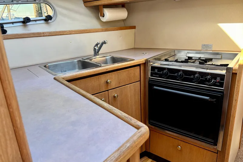 Slide: The Image of 1998 Bayliner 3388 Command Bridge Motoryacht kitchen with stove, double sink, and wooden cabinetry. - 20