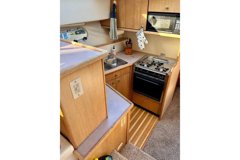 Slide: The Image of 1998 Bayliner 3388 Command Bridge Motoryacht kitchen with stove, sink, and microwave. - 21