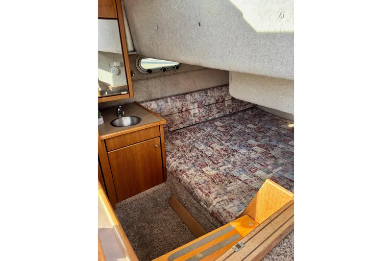 Slide: The Image of 1998 Bayliner 3388 Command Bridge Motoryacht cabin with bed, sink, and wooden cabinetry. - 31