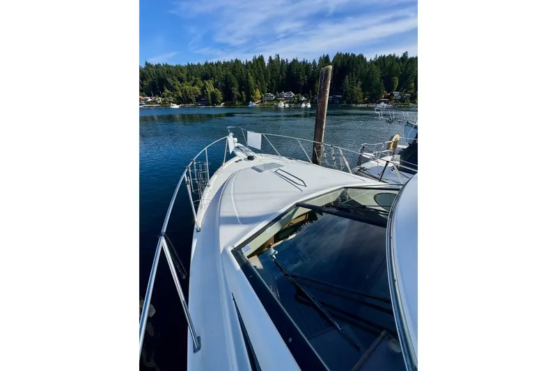 Slide: The Image of 1998 Bayliner 3388 Command Bridge Motoryacht on serene lake with forested shoreline. - 40