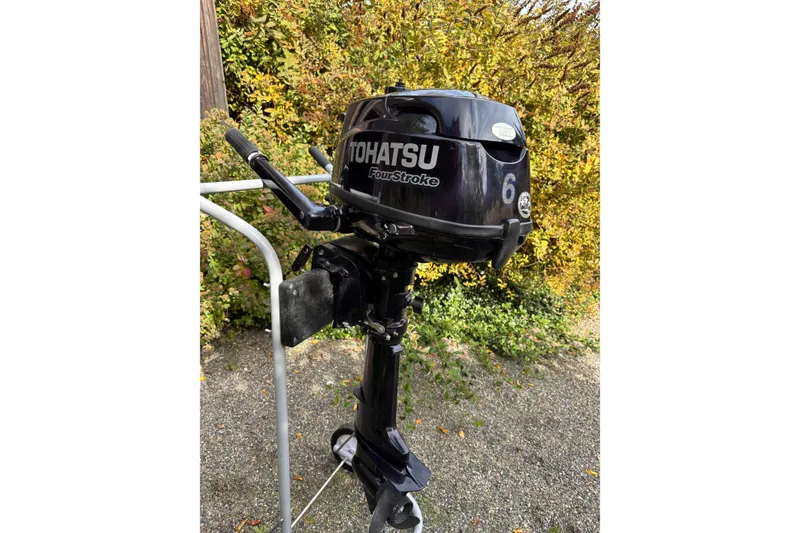 Slide: The Image of Tohatsu 6HP Four-Stroke outboard motor on a stand, outdoors with foliage background. - 44