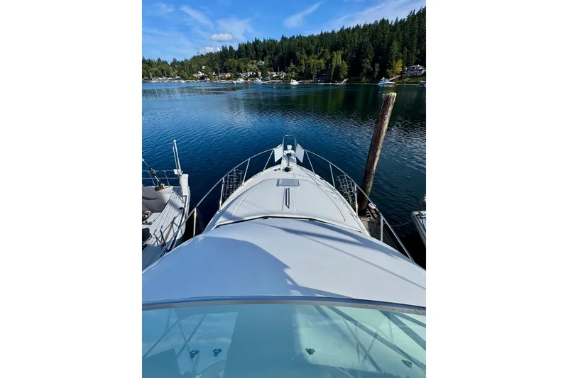 Slide: The Image of 1998 Bayliner 3388 Command Bridge Motoryacht docked on serene lake with forested shoreline. - 5