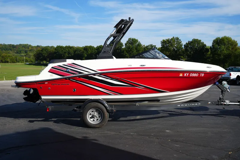 Slide: The Image of 2023 Bayliner VR5 Bowrider I/O boat on trailer, red and white design, parked outdoors. - 3
