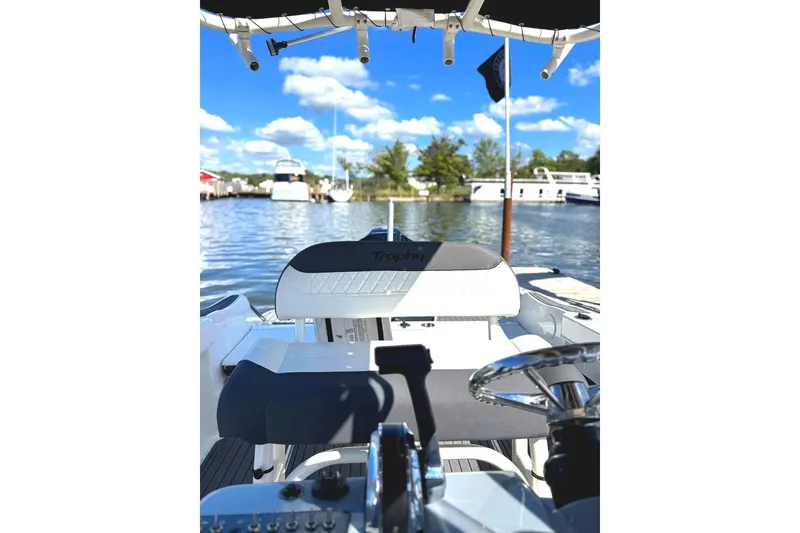 Slide: The Image of 2023 Bayliner Trophy T22CC boat interior with steering wheel, docked on a sunny day. - 24