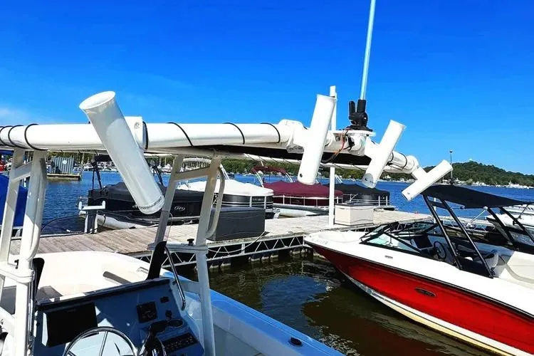Slide: The Image of 2023 Bayliner Trophy T22CC boat docked, featuring rod holders and a clear blue sky. - 27