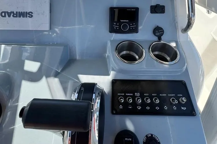 Slide: The Image of 2023 Bayliner Trophy T22CC boat dashboard with controls, cup holders, and electronic display. - 3