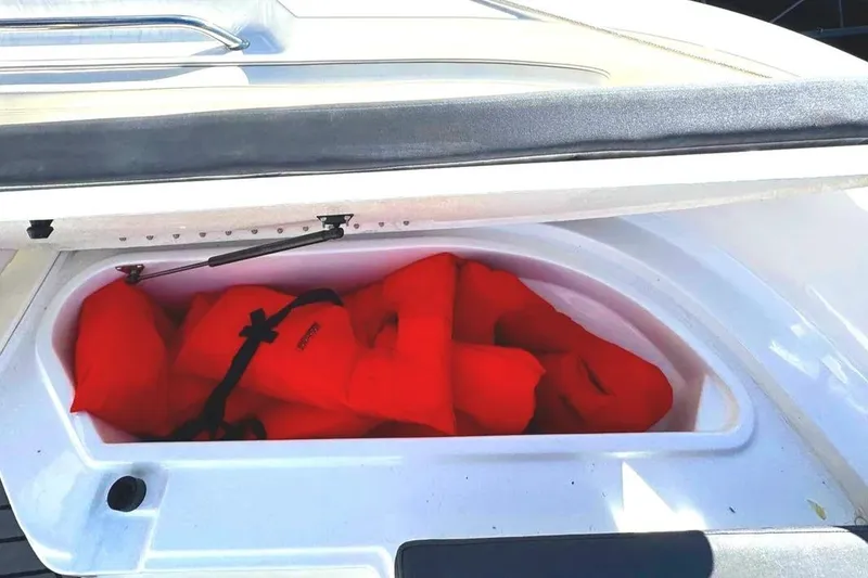 Slide: The Image of Storage compartment with red life jackets on a 2023 Bayliner Trophy T22CC boat. - 30