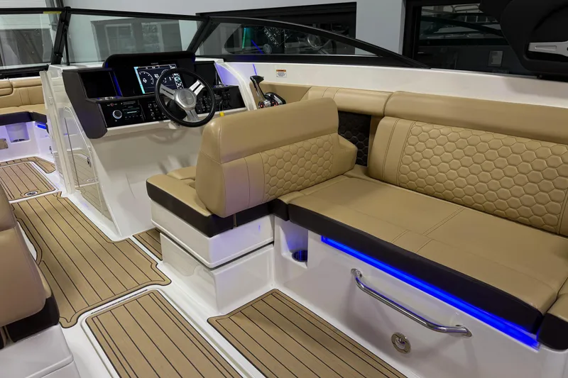 Slide: The Image of 2023 Sea Ray SDX 290 interior with beige seating, modern dashboard, and blue accent lighting. - 18