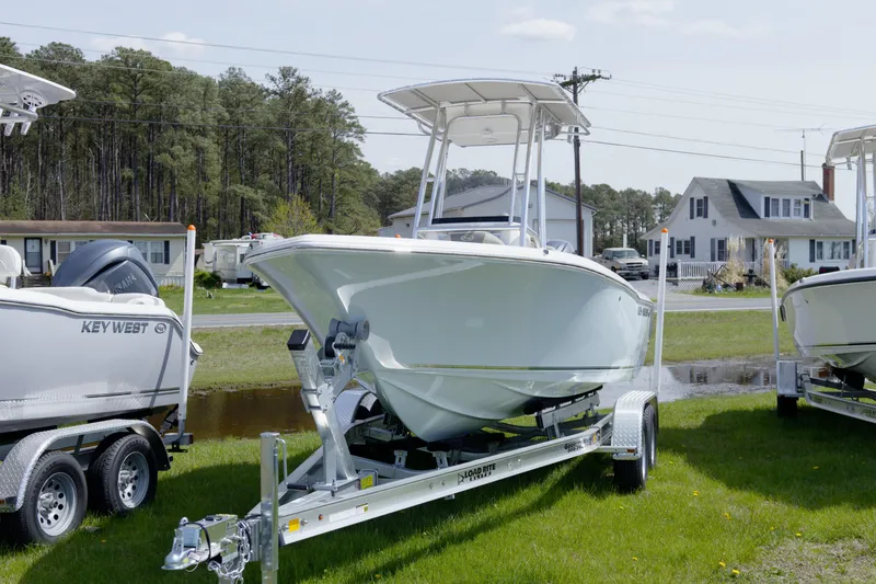 Slide: The Image of 2026 Key West 203 FS boat on trailer, parked on grass near houses and trees. - 11