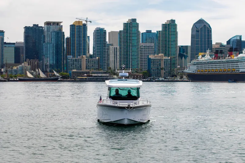 Slide: The Image of 2026 Axopar 29 XC Cross Cabin boat cruising near city skyline and large cruise ship. - 16