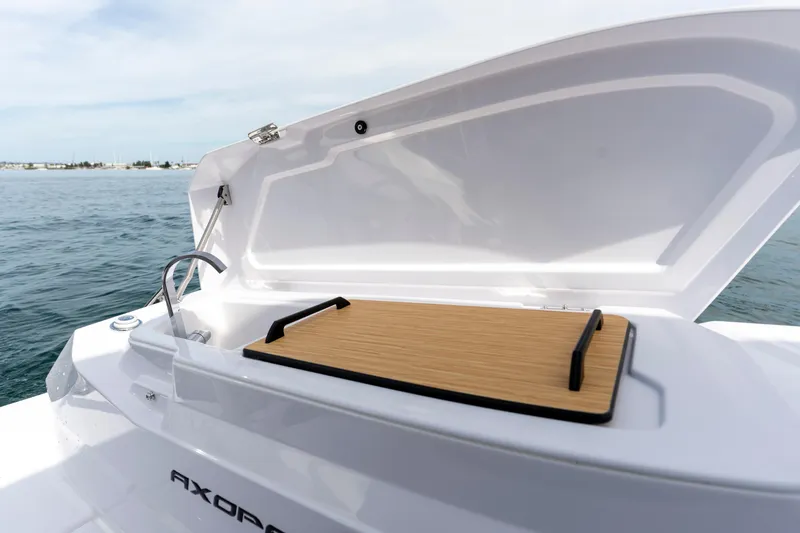 Slide: The Image of Open storage compartment on 2026 Axopar 29 XC Cross Cabin boat, with ocean backdrop. - 26