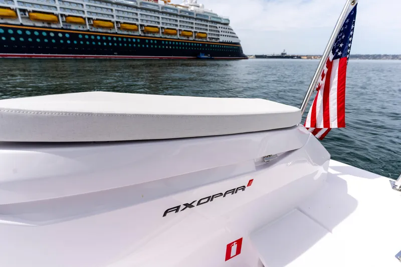 Slide: The Image of 2026 Axopar 29 XC Cross Cabin with American flag, near a large cruise ship. - 27