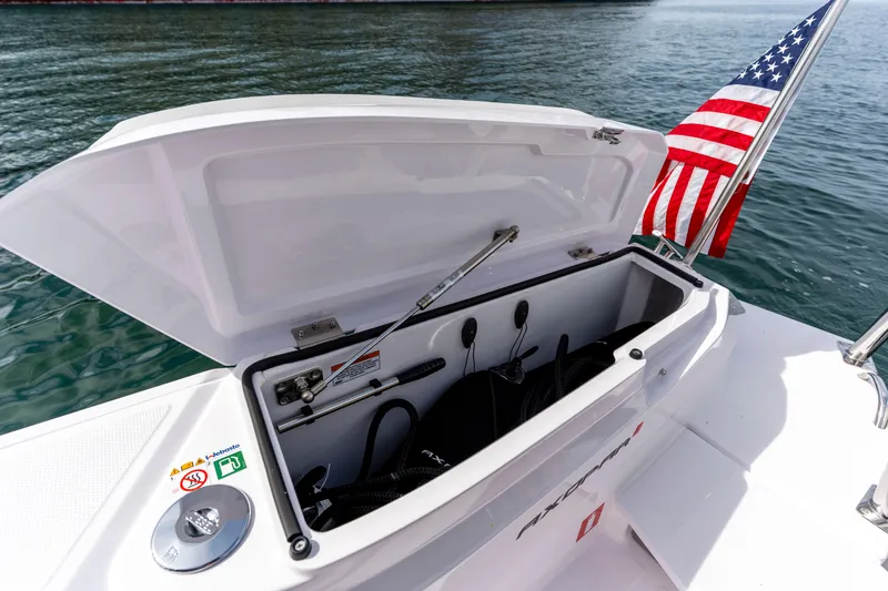 Slide: The Image of Open storage compartment on 2026 Axopar 29 XC Cross Cabin boat with American flag. - 28