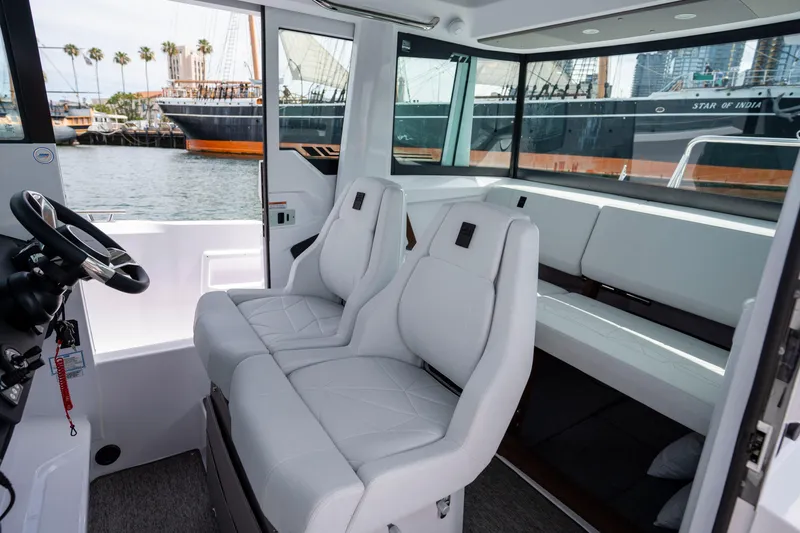 Slide: The Image of 2026 Axopar 29 XC Cross Cabin interior with white seating and harbor view. - 46
