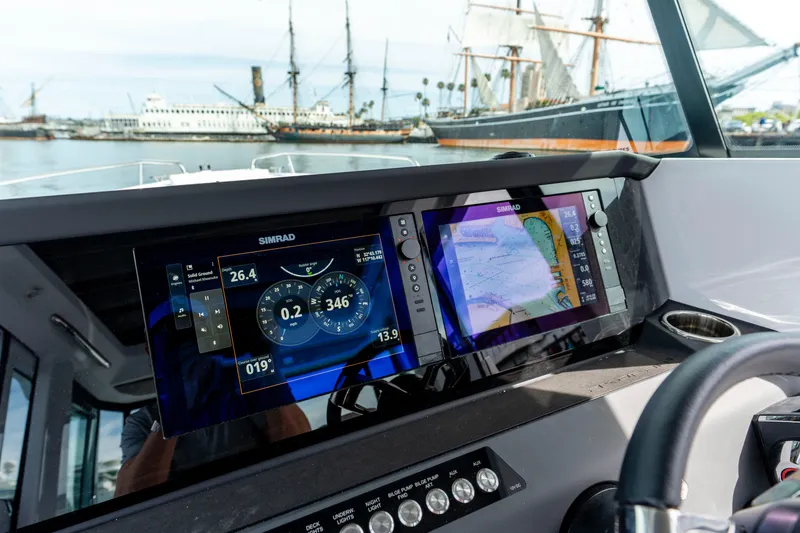 Slide: The Image of 2026 Axopar 29 XC Cross Cabin dashboard with navigation screens, docked near historic ships. - 51