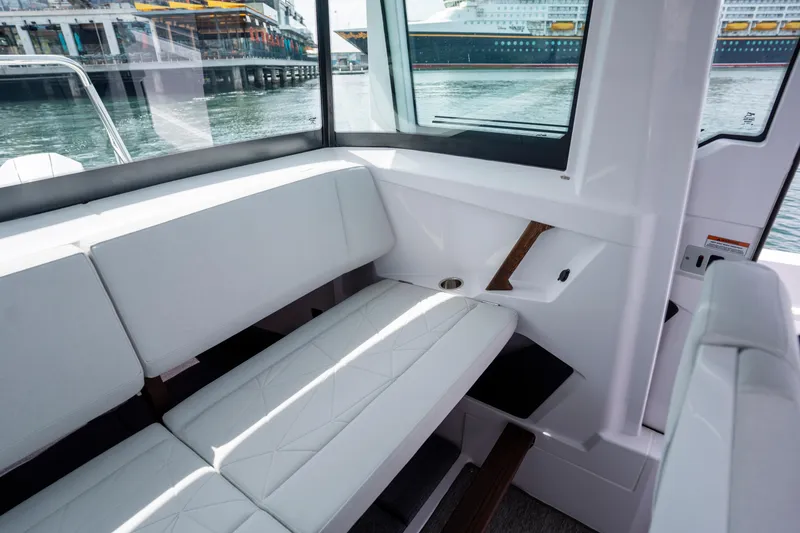 Slide: The Image of Interior of 2026 Axopar 29 XC Cross Cabin with white seating and waterfront view. - 55