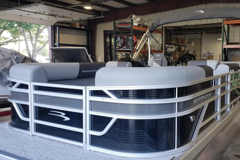 Slide: The Image of 2026 Bennington 20SL pontoon boat in a warehouse, featuring sleek design and comfortable seating. - 12