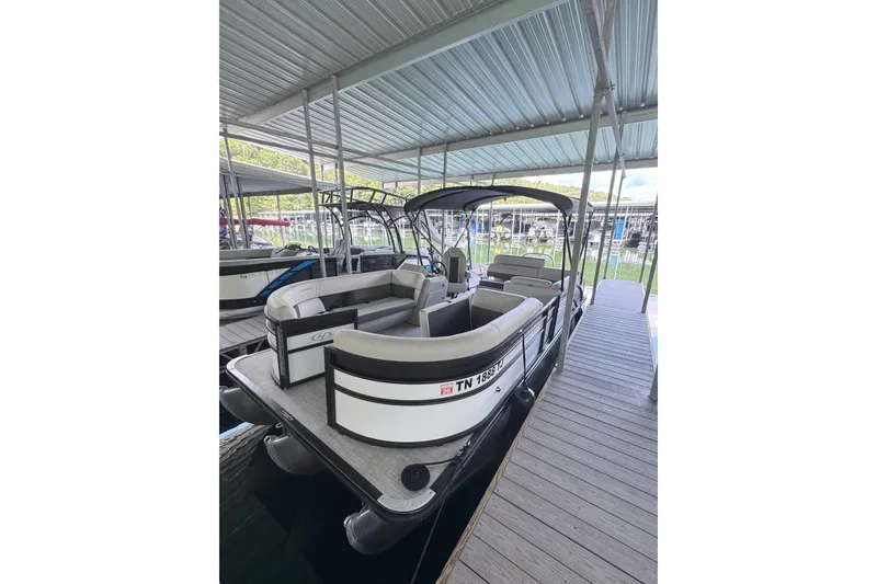 The Image of 2023 Harris Cruiser 230 pontoon boat docked under a covered marina. - 0