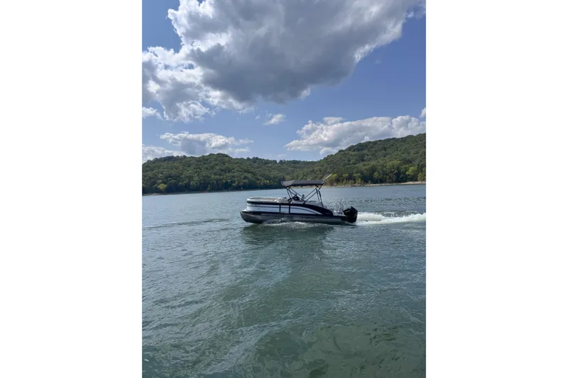 Slide: The Image of 2023 Harris Cruiser 230 pontoon boat cruising on a scenic lake under a cloudy sky. - 4