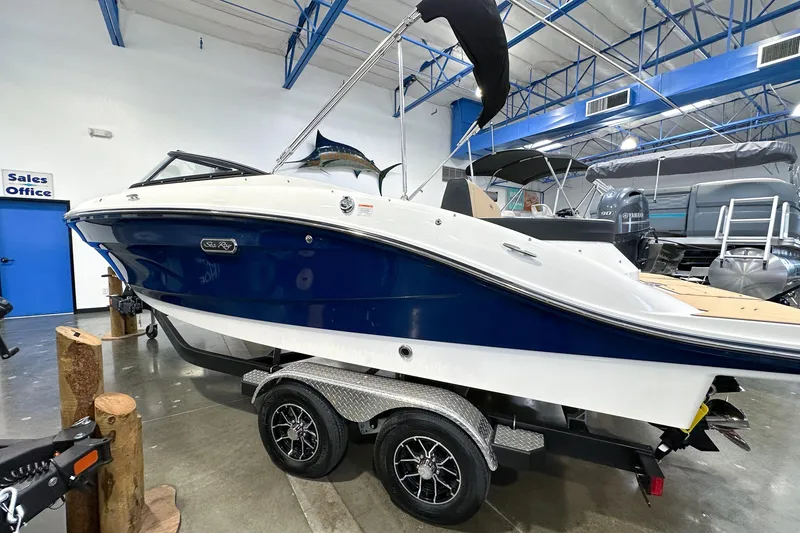 Slide: The Image of 2026 Sea Ray SPX 210 boat in showroom, blue and white design, on trailer. - 22