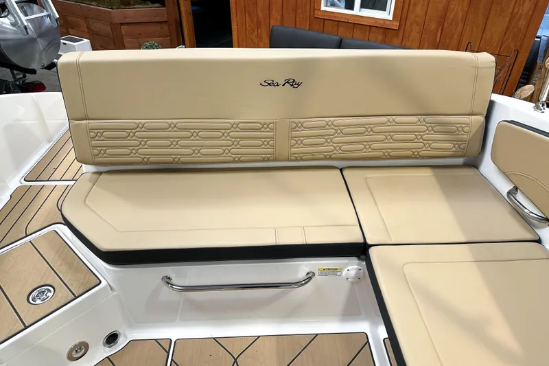 Slide: The Image of 2026 Sea Ray SPX 210 boat interior with beige cushioned seating and wood accents. - 6