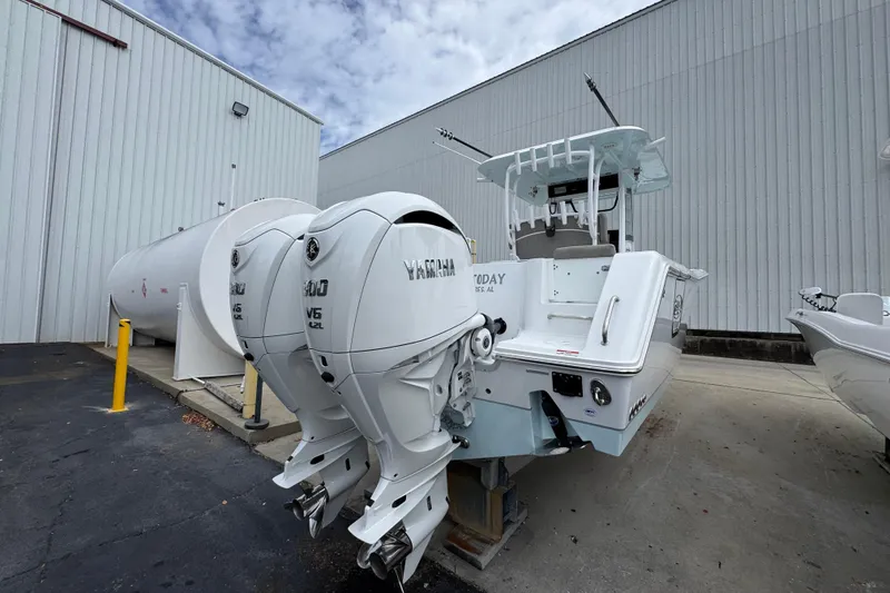 Slide: The Image of 2024 Sea Hunt Gamefish 28 boat with dual Yamaha V6 engines, parked near a large tank. - 10