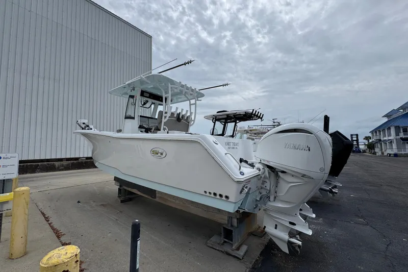 Slide: The Image of 2024 Sea Hunt Gamefish 28 boat with Yamaha engines, docked outdoors under cloudy skies. - 14