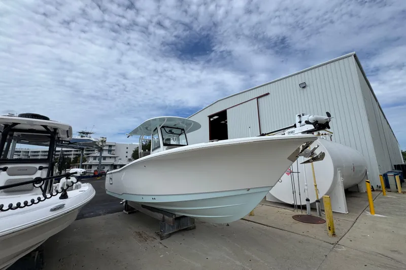 Slide: The Image of 2024 Sea Hunt Gamefish 28 boat outside a large storage building under a cloudy sky. - 7