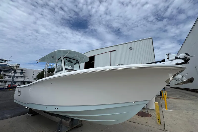 Slide: The Image of 2024 Sea Hunt Gamefish 28 boat docked near a warehouse under a cloudy sky. - 8