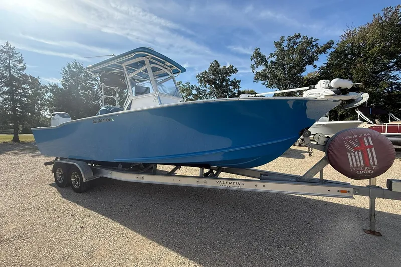 Slide: The Image of Blue 2020 Valentino 28CC boat on trailer, parked outdoors under clear sky. - 6