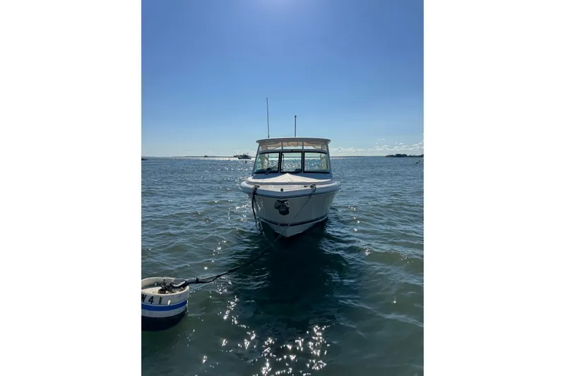 Slide: The Image of 2012 Pursuit DC 265 Dual Console boat anchored on calm water under clear blue sky. - 10