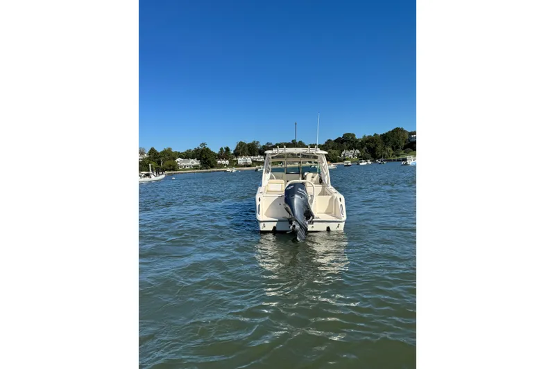 Slide: The Image of 2012 Pursuit DC 265 Dual Console boat on calm water under clear blue sky. - 12