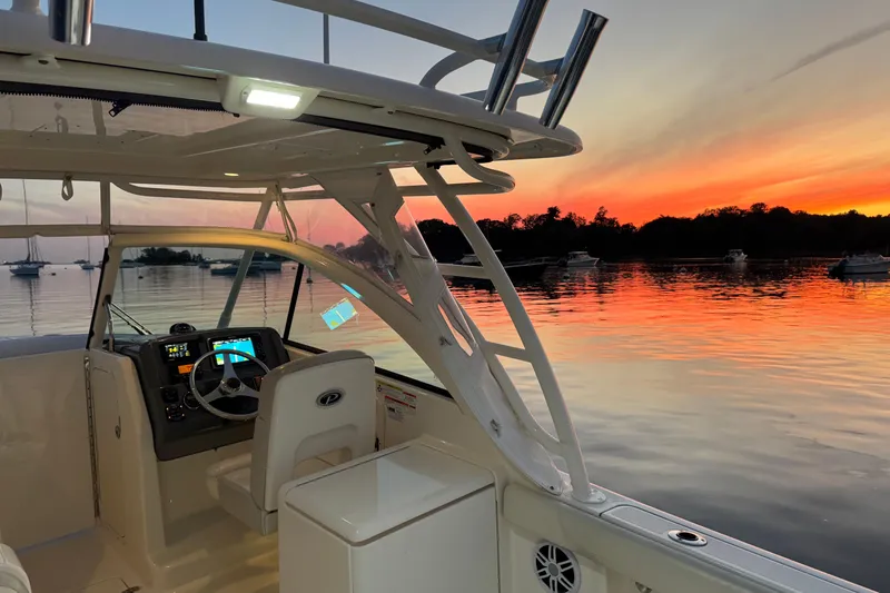 Slide: The Image of 2012 Pursuit DC 265 Dual Console boat at sunset on calm waters. - 4