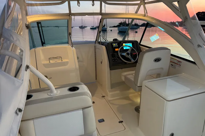 Slide: The Image of 2012 Pursuit DC 265 Dual Console boat interior with sunset view, featuring helm and seating. - 5