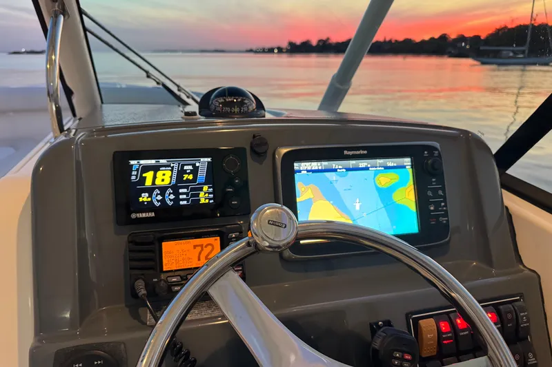 Slide: The Image of Cockpit view of 2012 Pursuit DC 265 boat with navigation screens at sunset. - 7