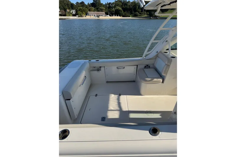 Slide: The Image of 2012 Pursuit DC 265 Dual Console boat interior, featuring seating and storage, on a calm lake. - 8