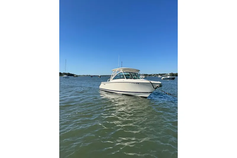 Slide: The Image of 2012 Pursuit DC 265 Dual Console boat anchored on calm water under clear blue sky. - 9
