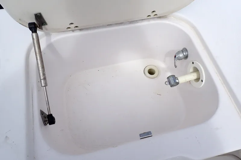 Slide: The Image of Open storage compartment on 2002 Pro-Line 33 WA boat, featuring a hydraulic lift and faucet. - 35