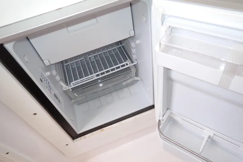 Slide: The Image of Open refrigerator inside a 2002 Pro-Line 33 WA boat, showing empty shelves and door compartments. - 75