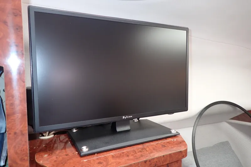 Slide: The Image of Flat-screen monitor on a wooden surface inside a 2002 Pro-Line 33 WA boat cabin. - 84