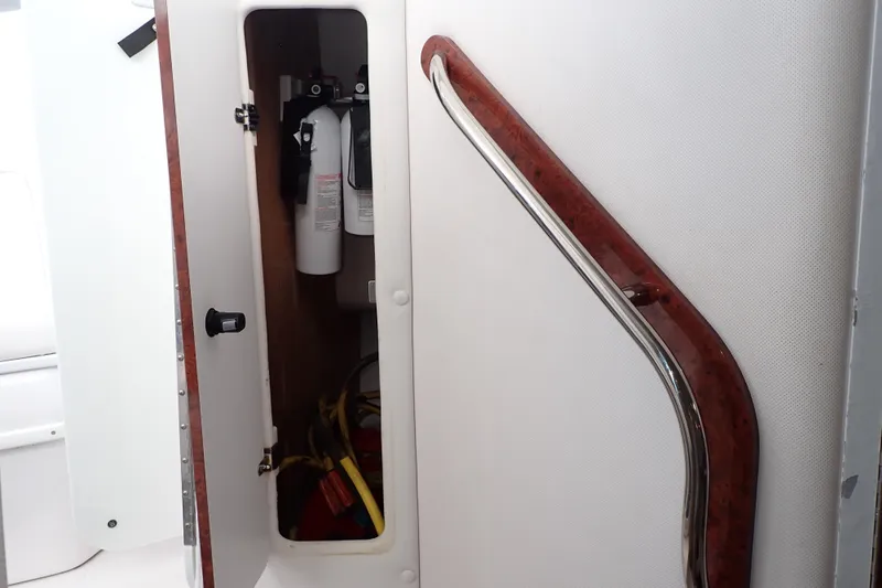 Slide: The Image of 2002 Pro-Line 33 WA boat interior with open storage compartment and fire extinguishers. - 95